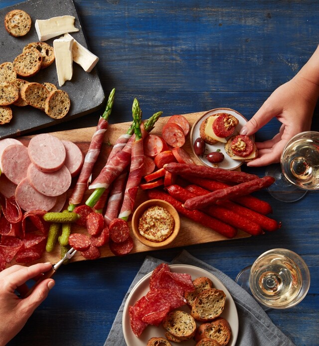 Charcuterie board covered with meat, cheese, crackers and spreads.