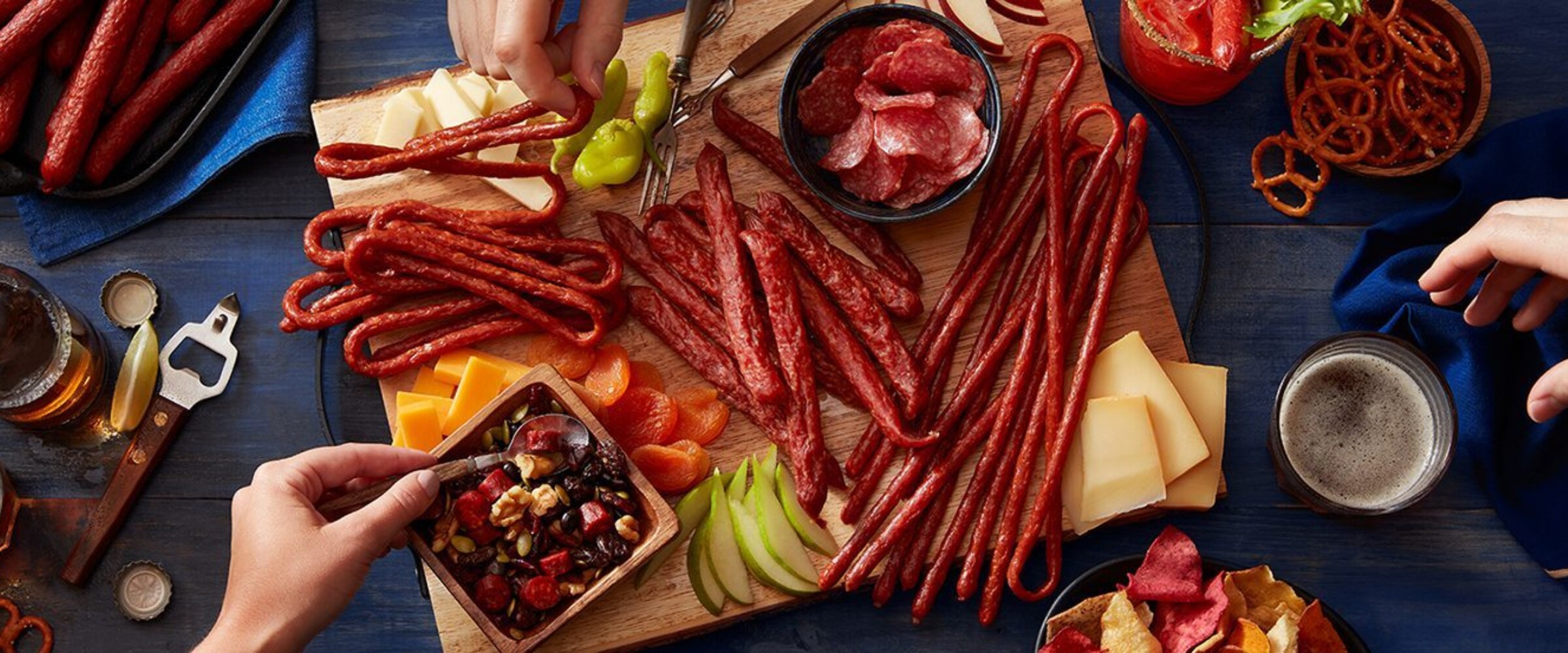 Hands reaching for meat snacks on a board