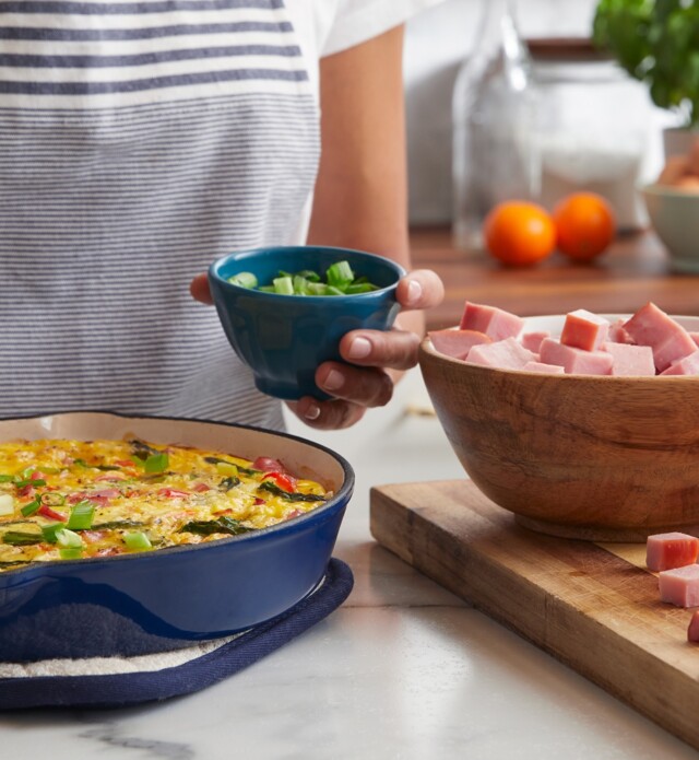 Person making quiche with ham.