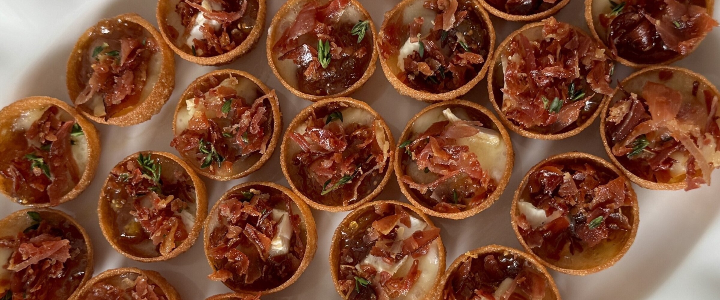 Dish of multiple mini brie and prosciutto cups