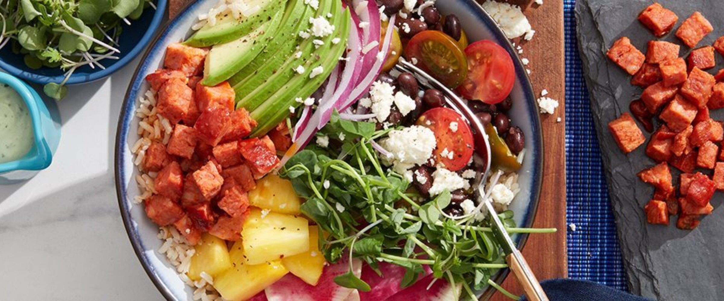 Chorizo, rice, avocado in a blue bowl on a cutting board