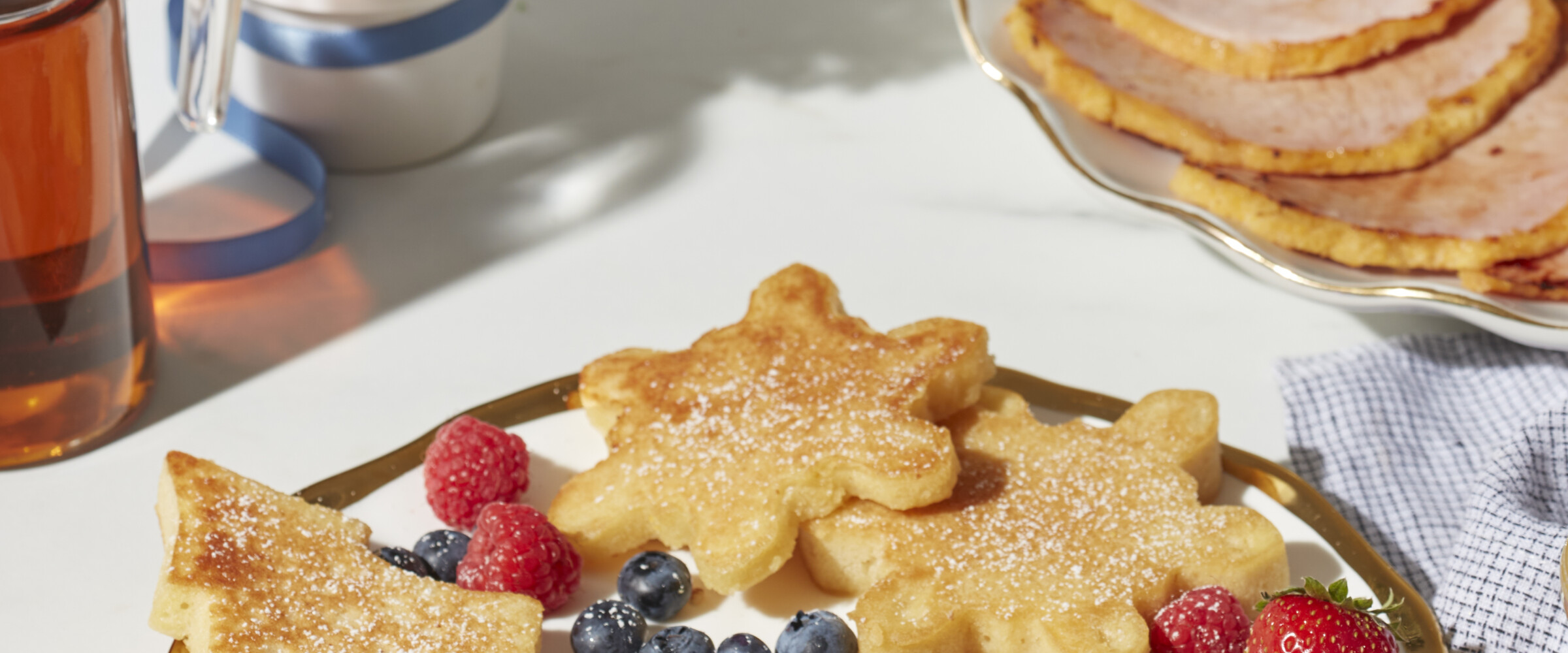 Snowflake and tree shaped pancakes served with berries and peameal bacon on a plate