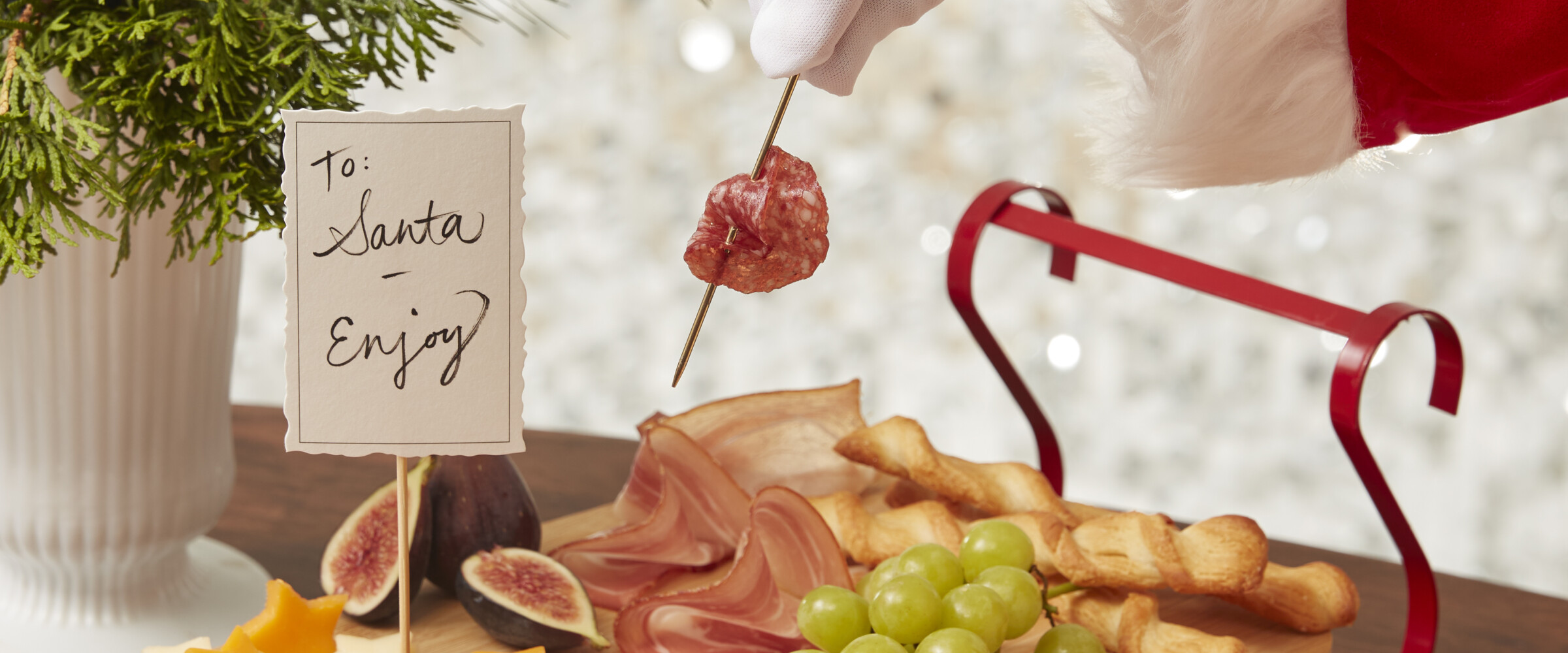 Charcuterie board with Santa taking some meat on a pick in hand