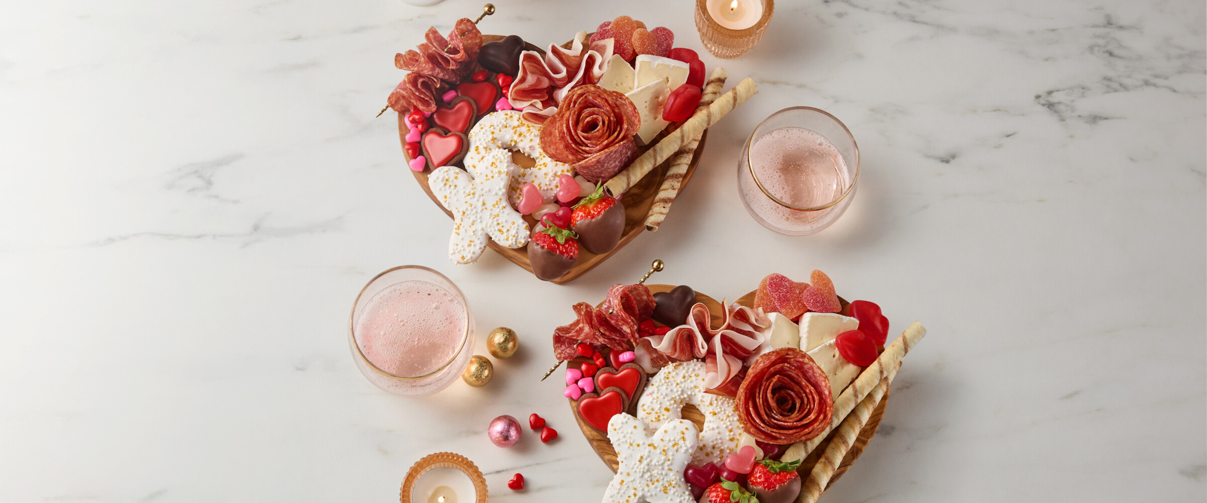 Heart shaped charcuterie boards with chocolate, sweets and meat.