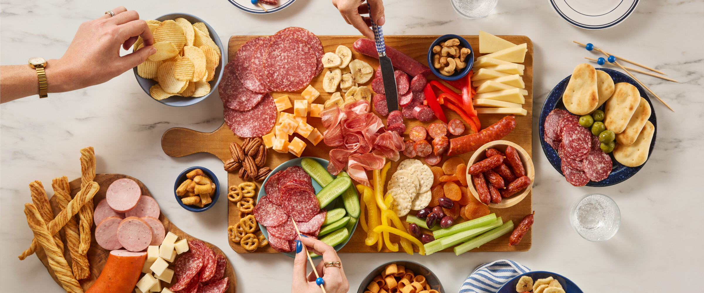 Large charcuterie board with lots of meat, cheeses, veggies and chips.