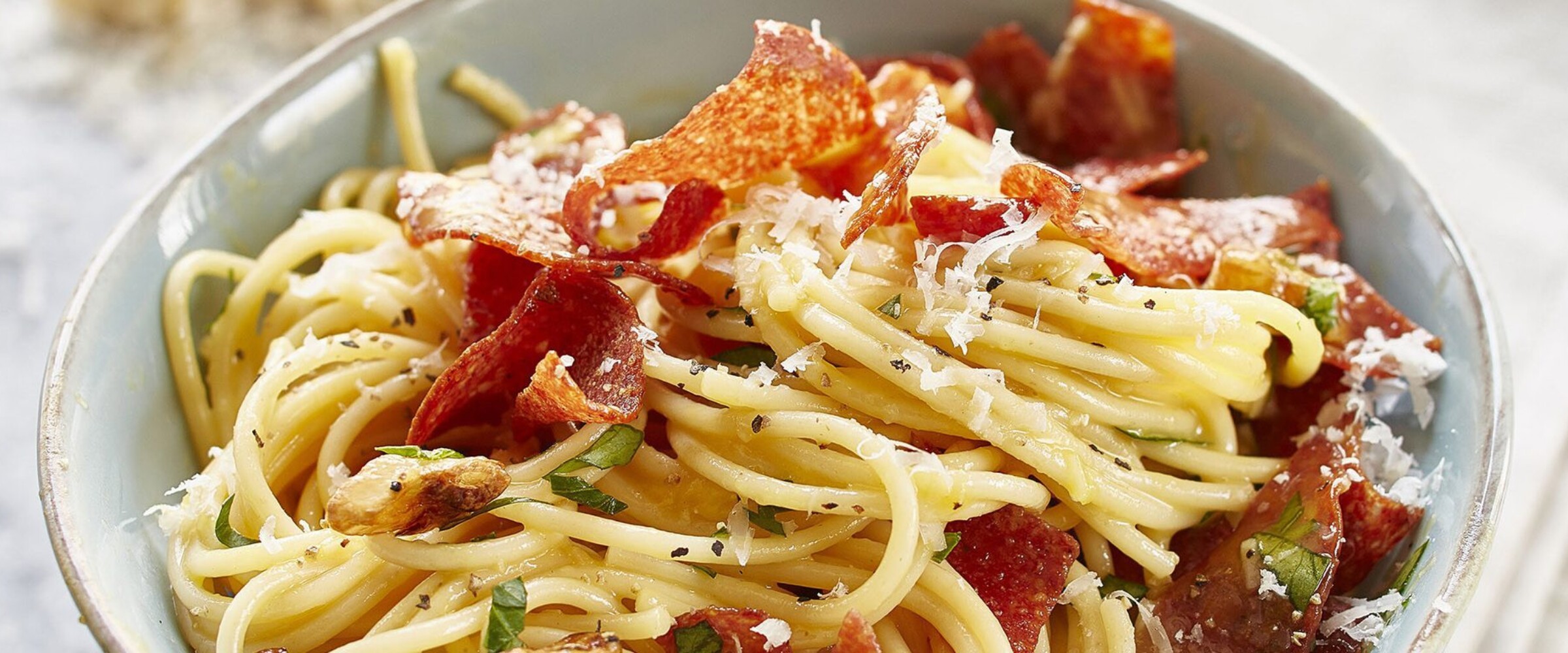 Carbonara with Salami on top in a white bowl