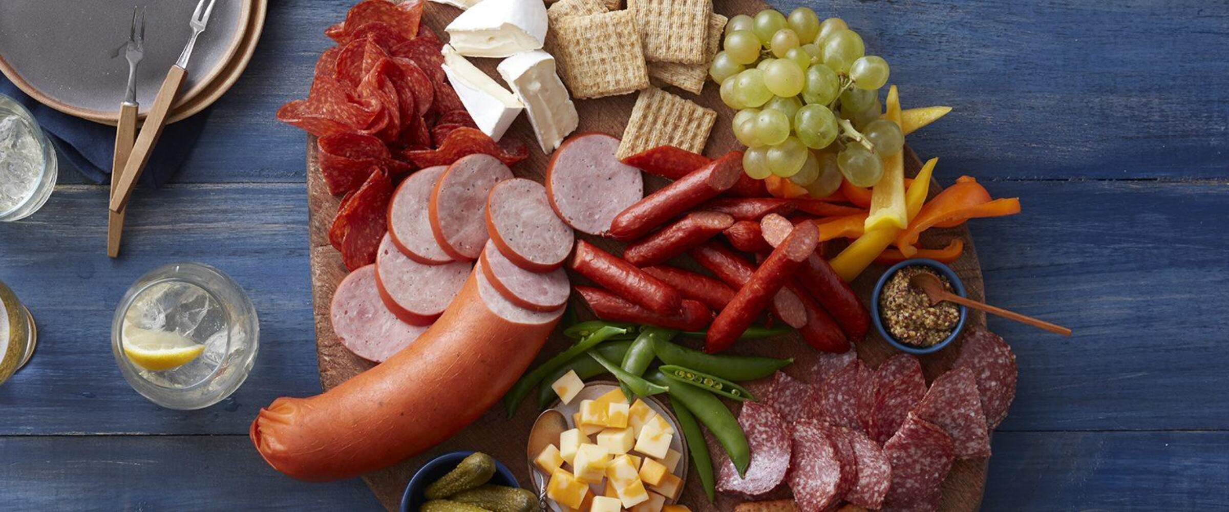 Large charcuterie board with meat, cheese, fruit, vegetables and crackers
