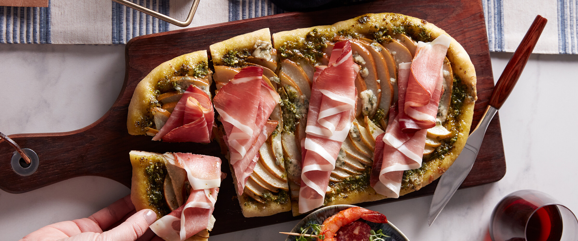 Prosciutto and pear flatbread on a board with holiday decorations