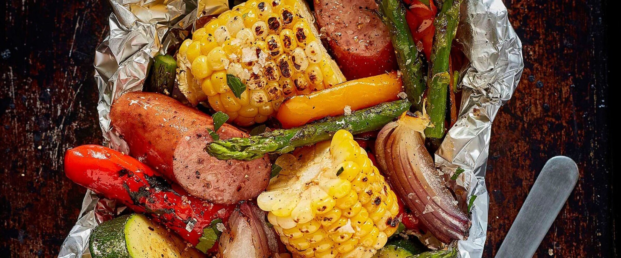 Grillwurst sausage and vegetables grilled in a foil packet