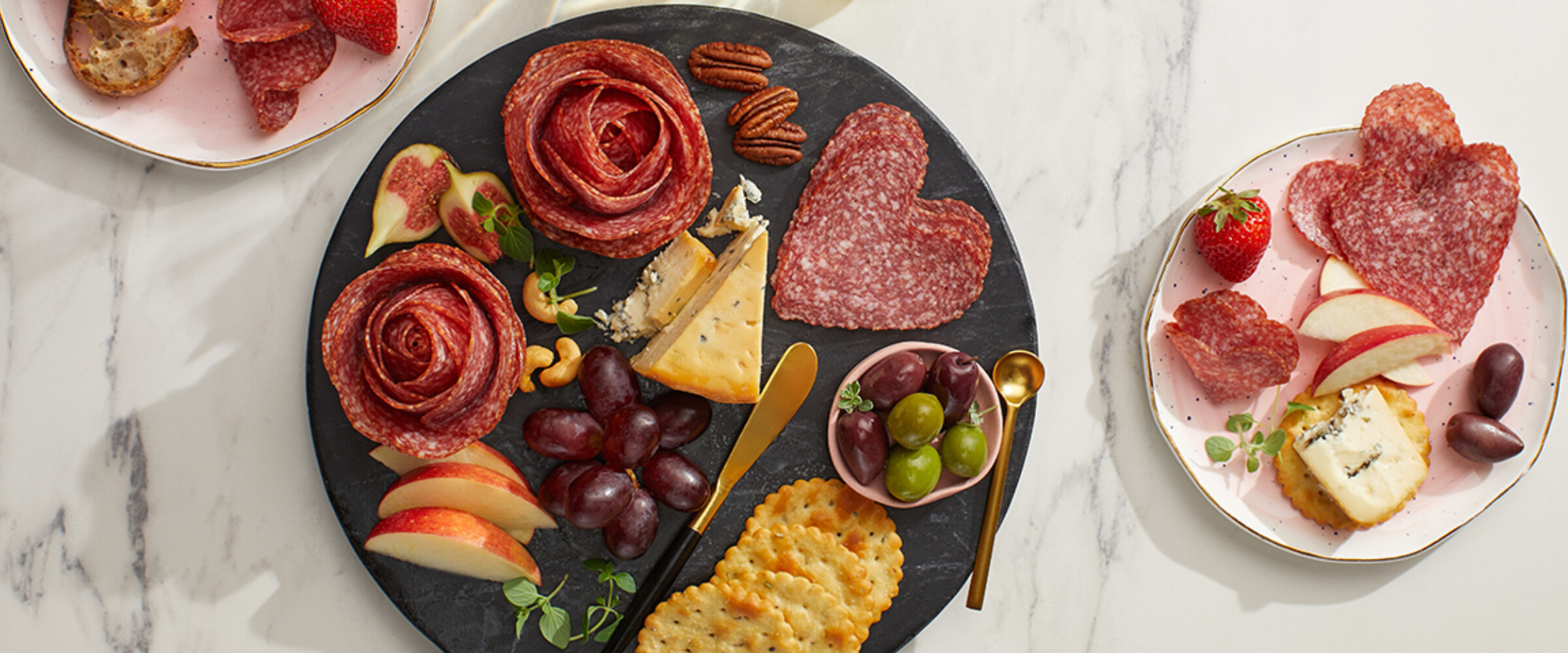 heart shaped salami and flower roses on a black grazing board.
