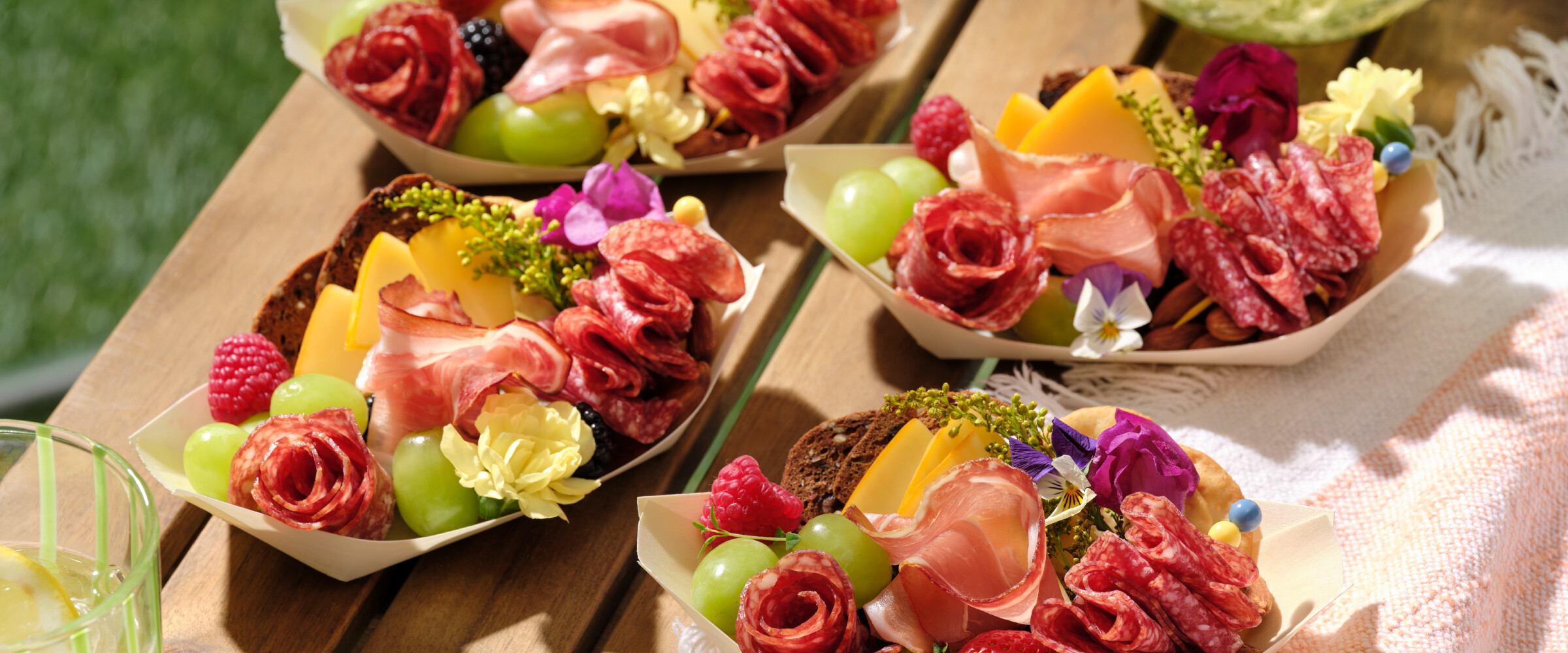 Charcuterie boats on an outdoor picnic table.