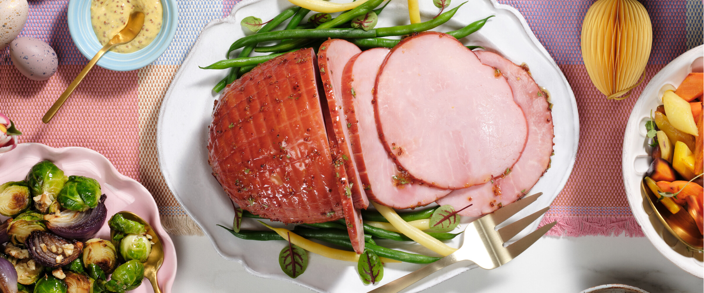 Ham cut in slices on a platter dish for serving with Easter decor on the table.