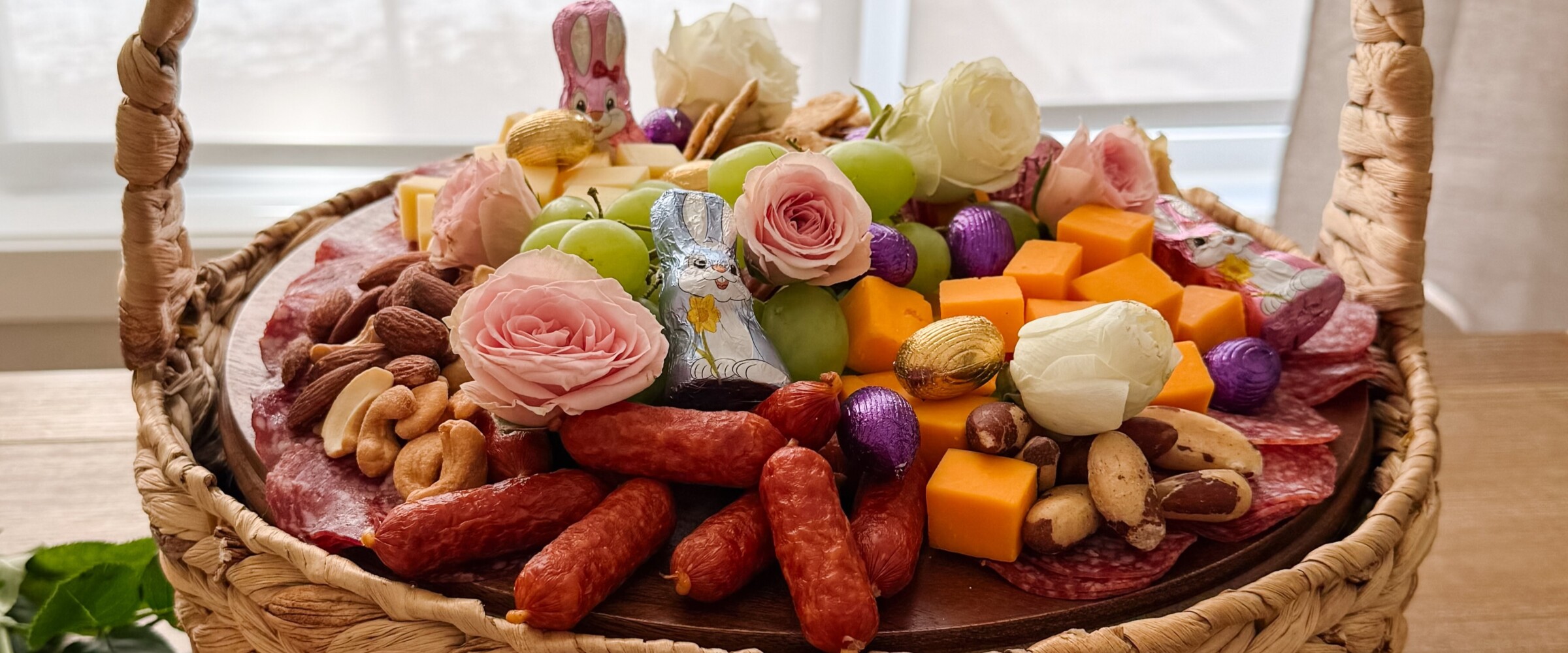 Easter basket filled with charcuterie components and Easter chocolates.