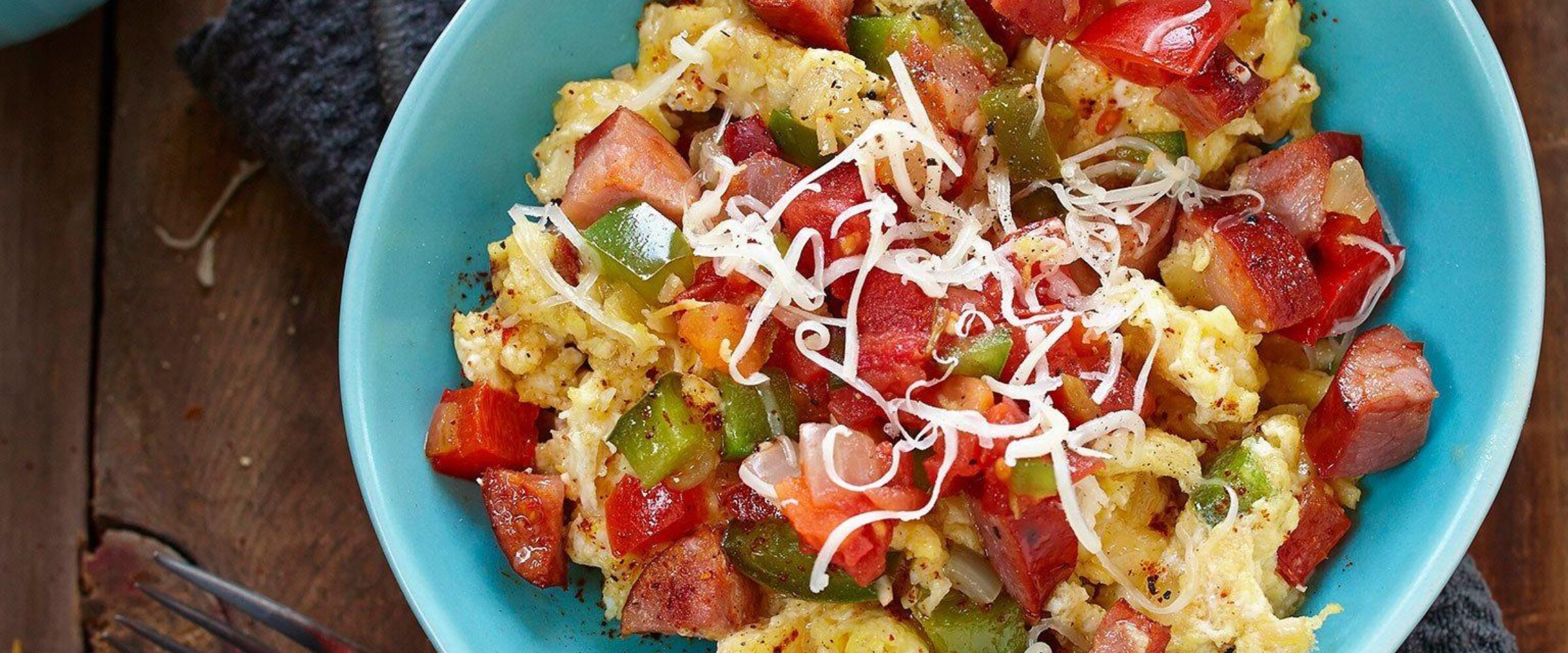 Scrambled eggs with chorizo and vegetables in a blue bowl