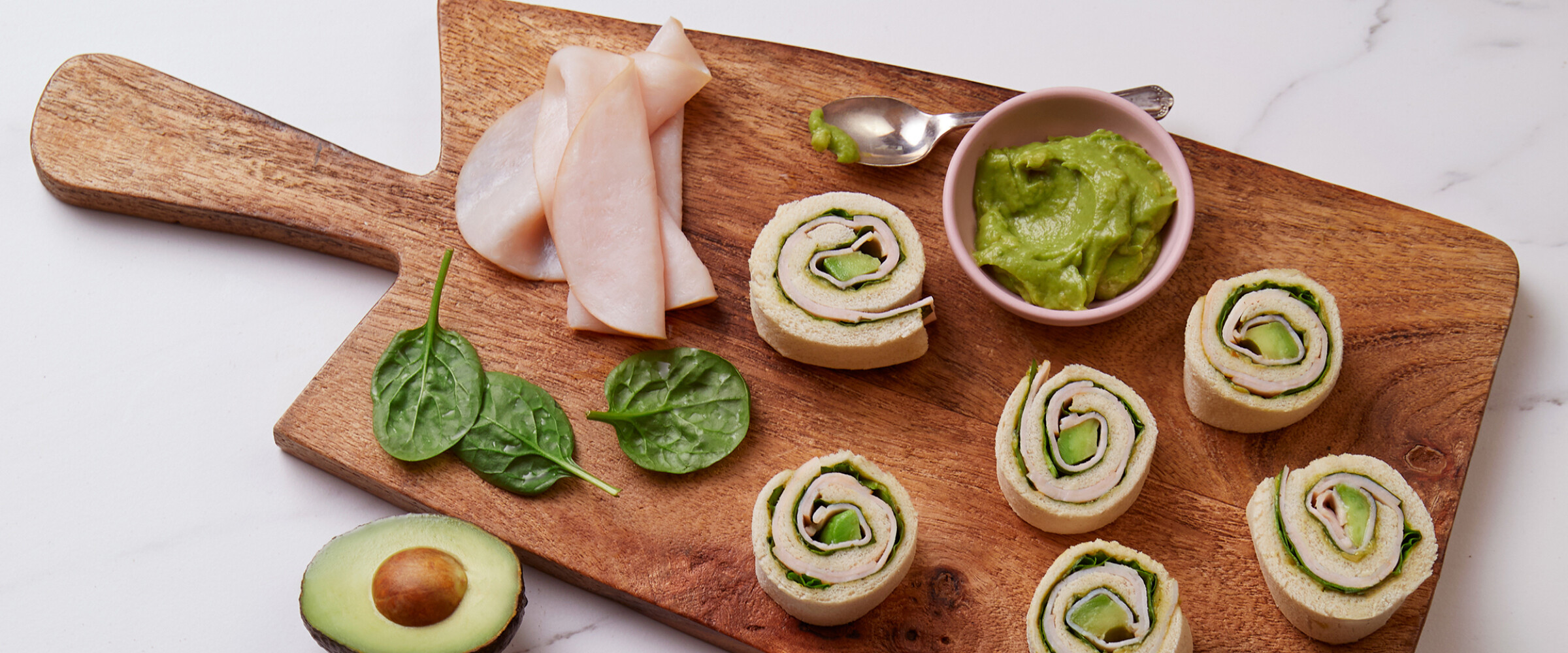 turkey and avacado rolls on a cutting board with guac