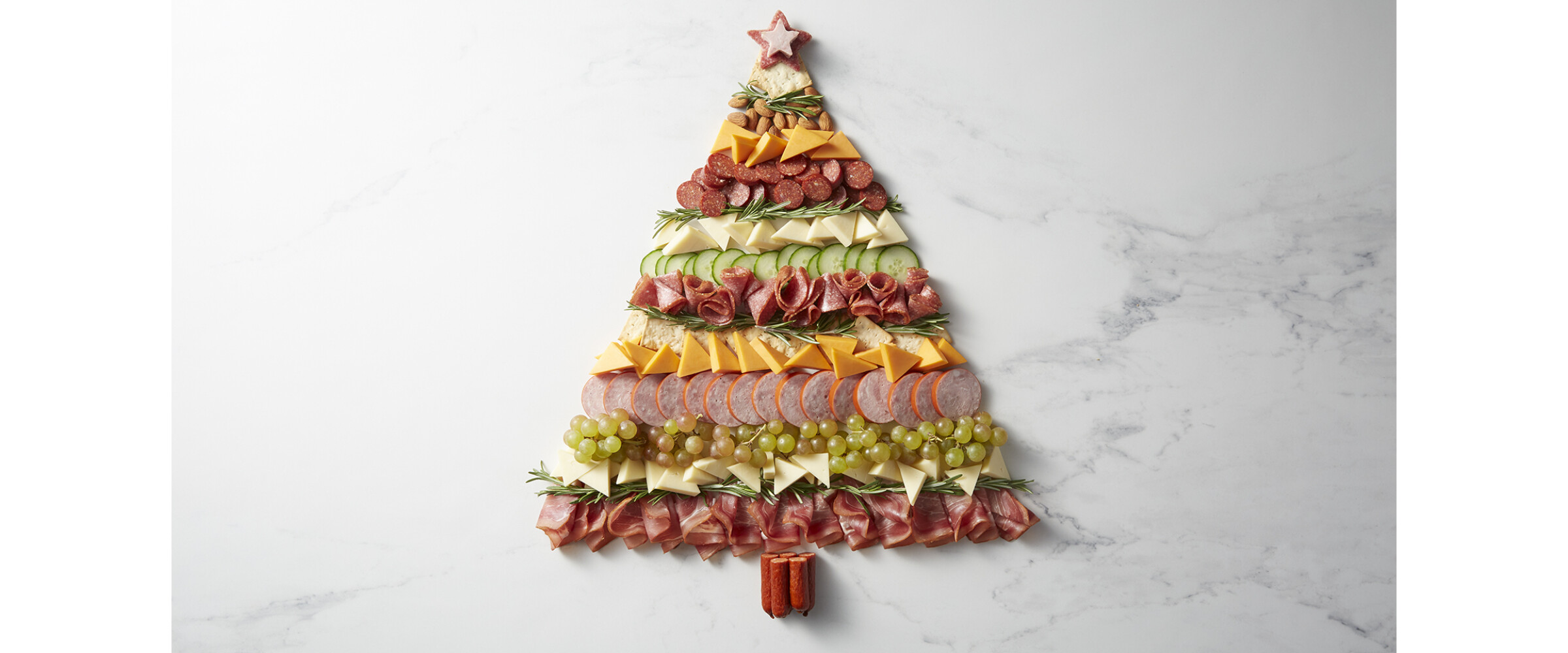 Charcuterie meats, cheeses, and fruits in the shape of a christmas tree