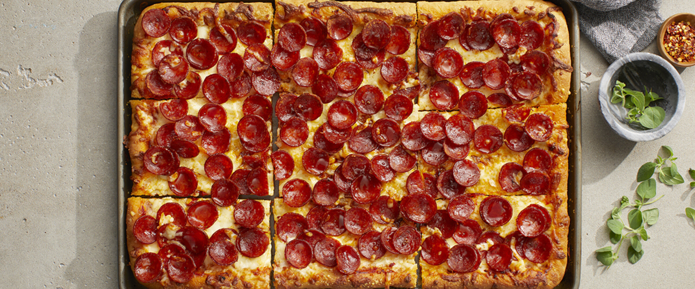 pizzeria style pepperoni pizza on a grey surface