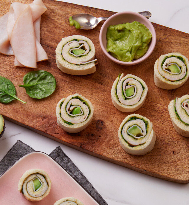 turkey and avacado rolls on a cutting board with guac