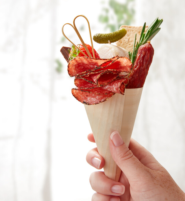 Hand holding up cone with charcuterie in it