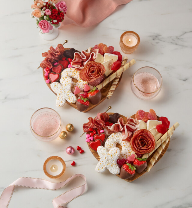 Heart shaped charcuterie boards with chocolate, sweets and meat.