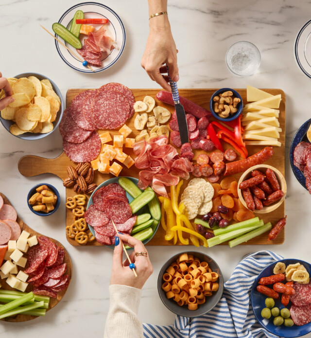 Large charcuterie board with lots of meat, cheeses, veggies and chips.