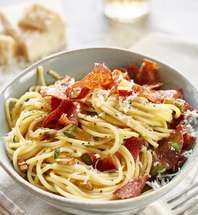 Carbonara with Salami on top in a white bowl