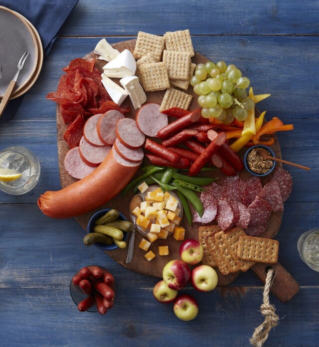 Large charcuterie board with meat, cheese, fruit, vegetables and crackers