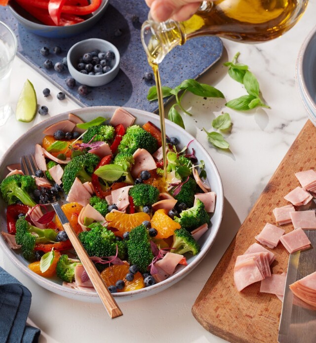 Person pouring dressing on salad