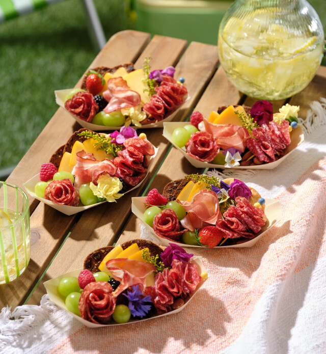 Charcuterie boats on an outdoor picnic table.