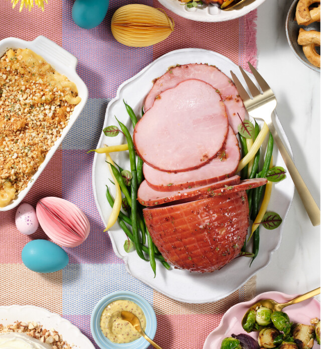 Ham cut in slices on a platter dish for serving with Easter decor on the table.