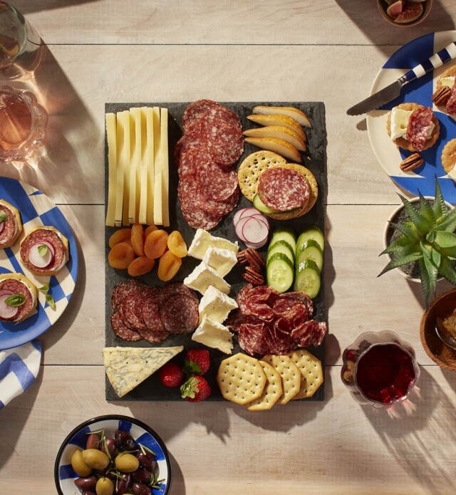Charcuterie board with salami and cheese and fruit on a patio table