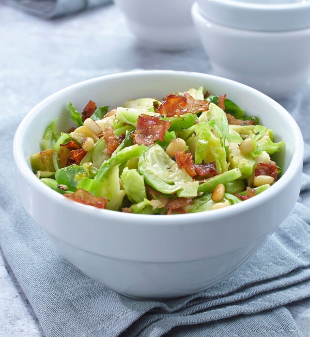 Brussel Sprouts shredded with Speck Prosciutto in a white bowl