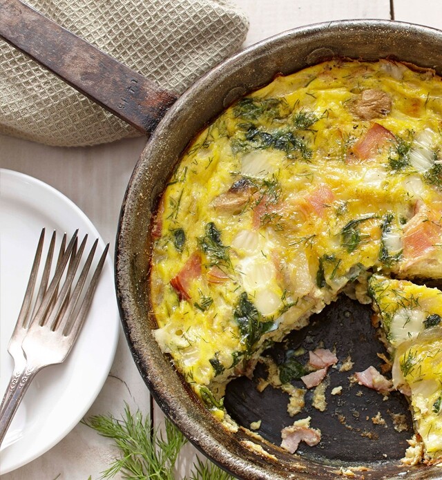 Close-up view of quiche with smoked ham and mushrooms next to white dinner plate.